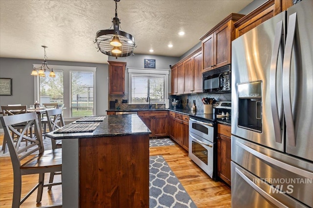 1063 Hitchcock St, Meridian, ID 83646 - kitchen with stainless steel appliances, a center island, a sink, light wood-style floors, and decorative backsplash