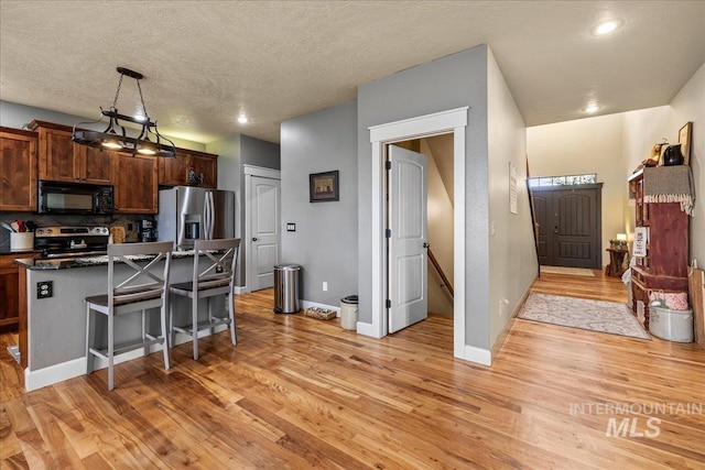 1063 Hitchcock St, Meridian, ID 83646 - kitchen with light wood finished floors, stainless steel appliances, a kitchen breakfast bar, a center island, and backsplash