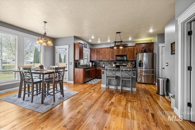 1063 Hitchcock St, Meridian, ID 83646 - kitchen with dark countertops, light wood-type flooring, a textured ceiling, appliances with stainless steel finishes, and a notable chandelier