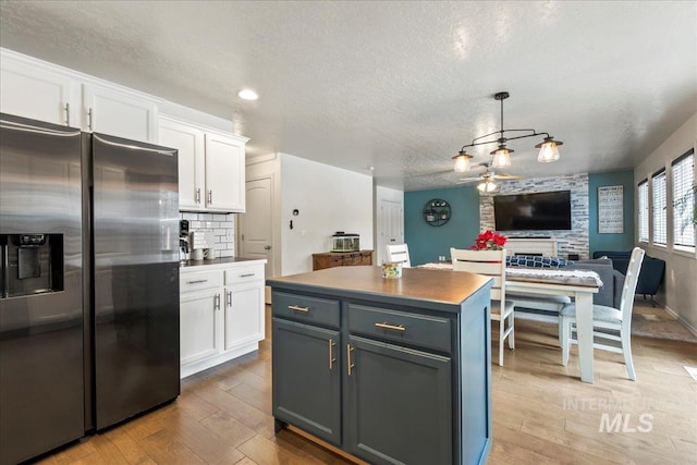 kitchen with decorative light fixtures, a center island, white cabinets, and stainless steel fridge with ice dispenser