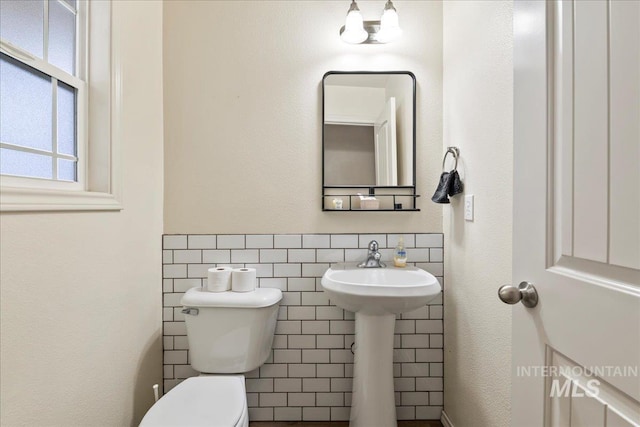 bathroom with tile walls and toilet