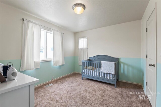 bedroom featuring a crib and carpet