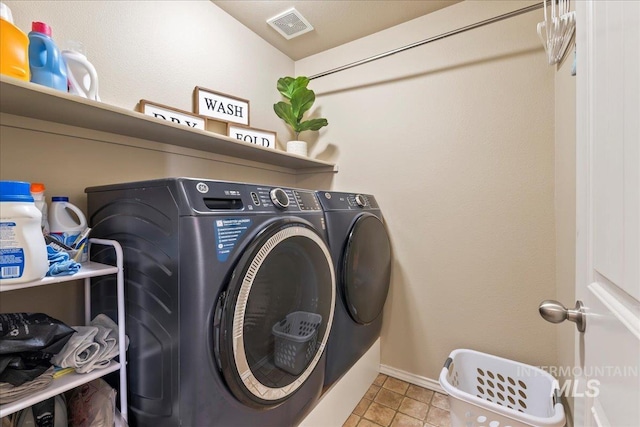 laundry room with washer and dryer and light tile patterned floors