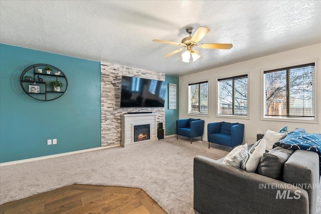 carpeted living room featuring ceiling fan, a large fireplace, and a textured ceiling