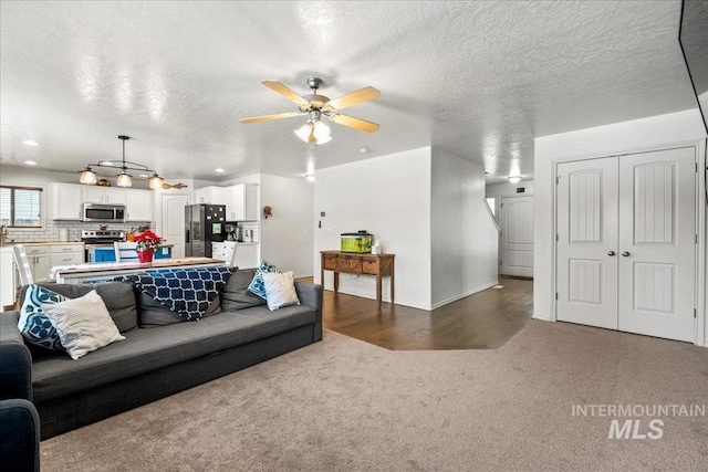 carpeted living room featuring ceiling fan and a textured ceiling