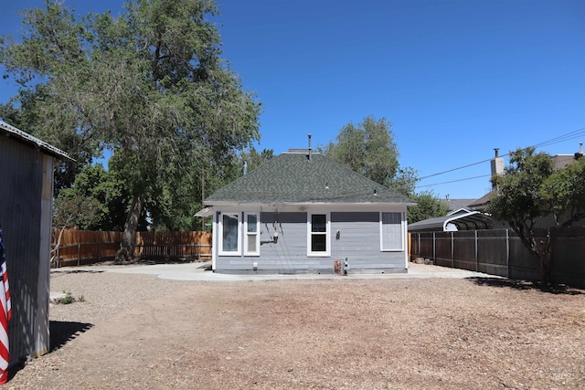 585 N 5th E, Mountain Home, ID 83647 - rear view of house featuring a fenced backyard, roof with shingles, and a detached carport