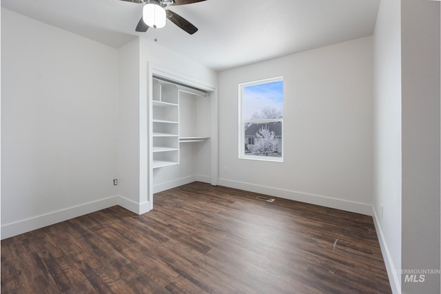 unfurnished bedroom with a closet, dark hardwood / wood-style floors, and ceiling fan