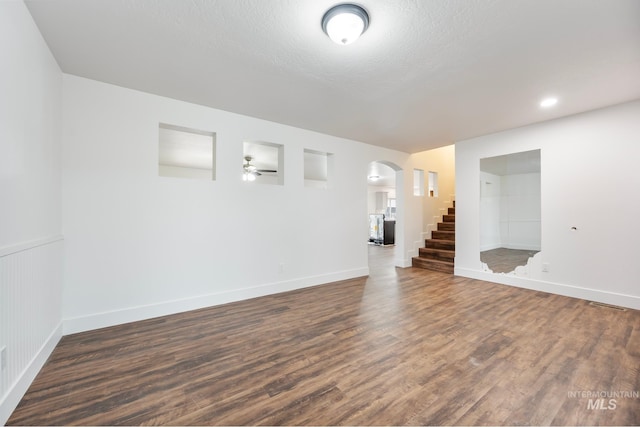 unfurnished living room featuring ceiling fan, dark wood-type flooring, and a textured ceiling