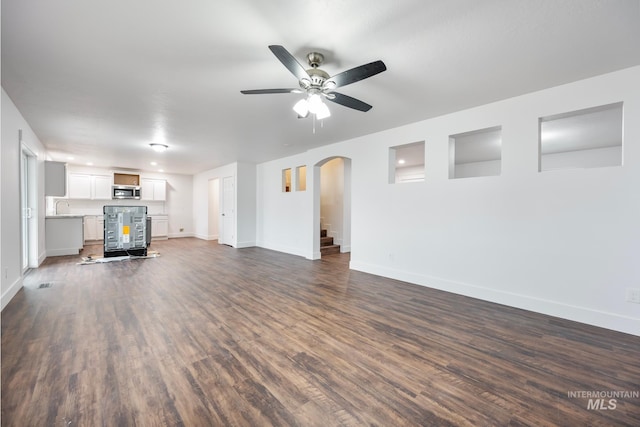 unfurnished living room featuring ceiling fan and dark hardwood / wood-style floors