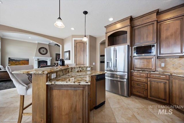 kitchen with a kitchen bar, pendant lighting, built in microwave, a kitchen island, and stainless steel fridge