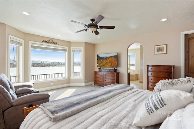 bedroom with light carpet, ceiling fan, and ensuite bath