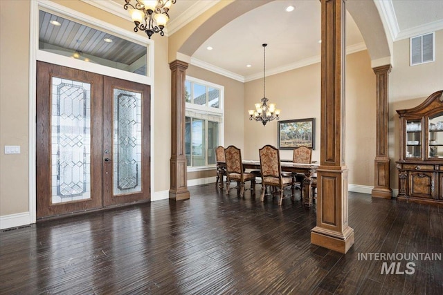 foyer entrance with an inviting chandelier, decorative columns, dark hardwood / wood-style floors, french doors, and ornamental molding