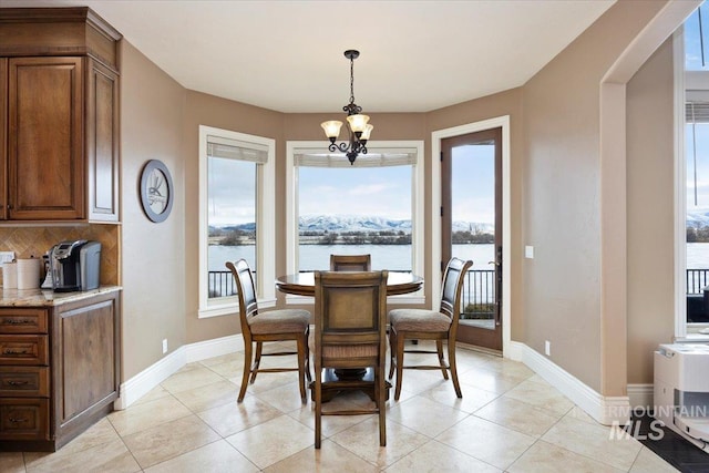 tiled dining area with a water view and an inviting chandelier