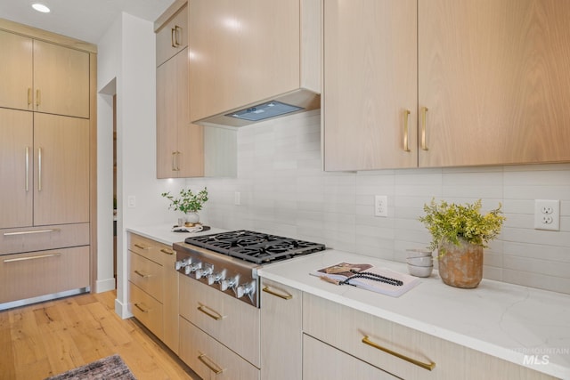 kitchen featuring backsplash, stainless steel gas cooktop, light hardwood / wood-style floors, light stone countertops, and light brown cabinets