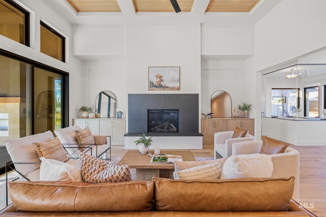 living room with coffered ceiling, wood-type flooring, a chandelier, a towering ceiling, and beam ceiling