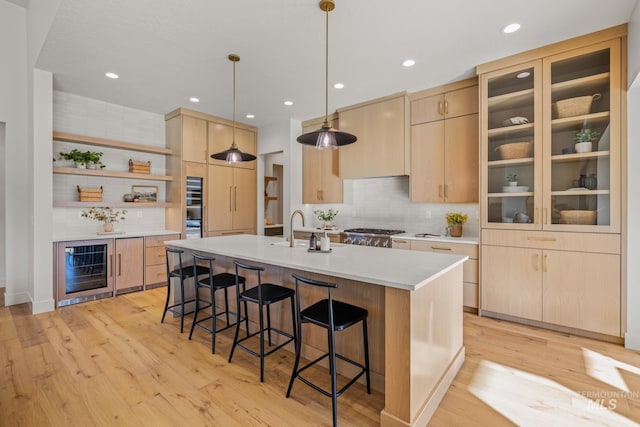 kitchen with pendant lighting, light hardwood / wood-style flooring, beverage cooler, and light brown cabinets