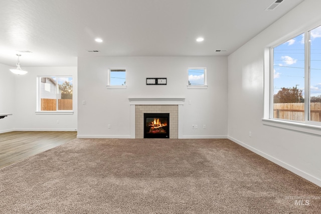 unfurnished living room with a tile fireplace, hardwood / wood-style flooring, and a wealth of natural light