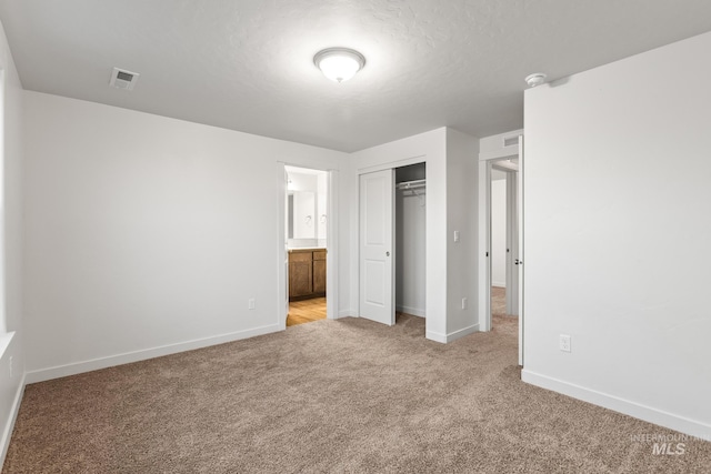 unfurnished bedroom featuring a textured ceiling, light colored carpet, and a closet