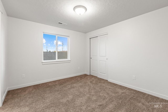 unfurnished bedroom with carpet flooring, a textured ceiling, and a closet