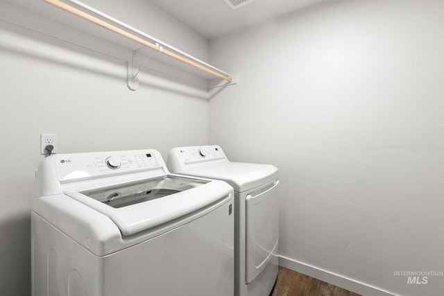 laundry area with washing machine and clothes dryer and dark hardwood / wood-style floors