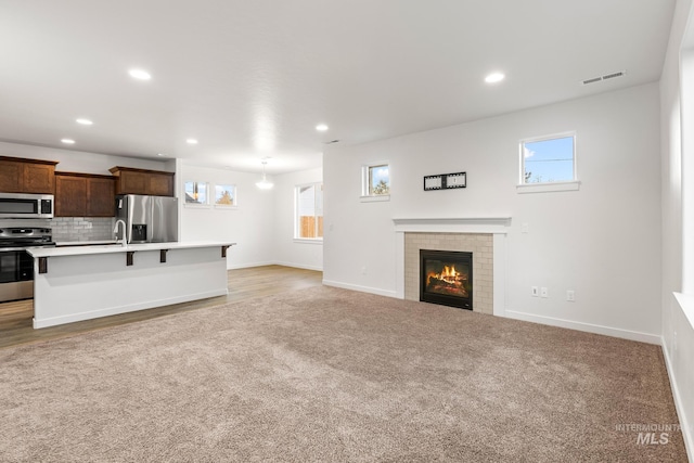 carpeted living room with a tiled fireplace and sink