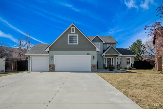 view of front of home with stone siding, fence, a front lawn, and concrete driveway