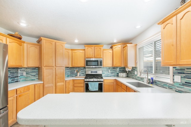 kitchen featuring light brown cabinets, appliances with stainless steel finishes, light countertops, and a sink