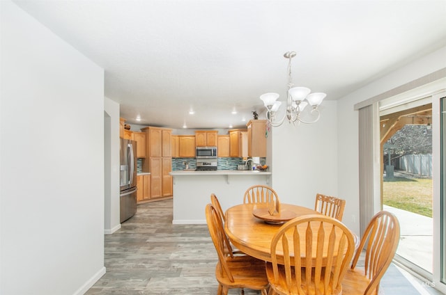 dining area with baseboards, recessed lighting, an inviting chandelier, and light wood-style floors