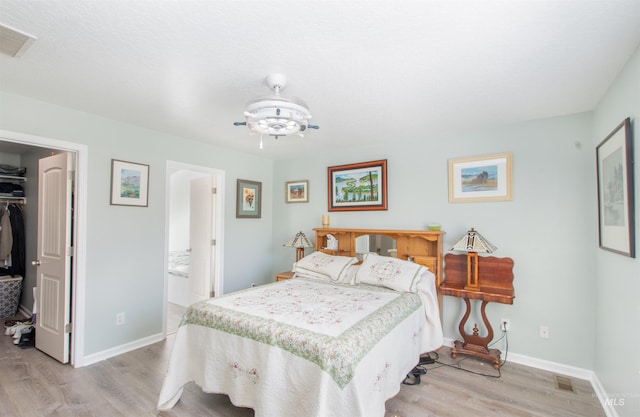 bedroom featuring light wood finished floors, a spacious closet, visible vents, and a closet