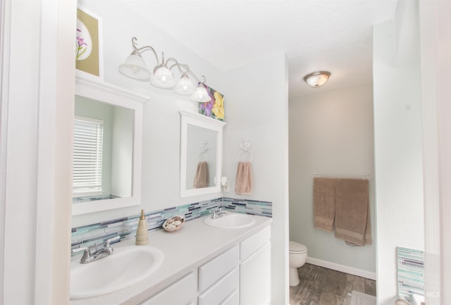 full bathroom featuring double vanity, wood finished floors, a sink, and toilet