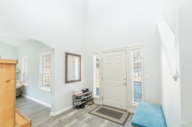 entrance foyer featuring arched walkways, a healthy amount of sunlight, and light wood-style flooring