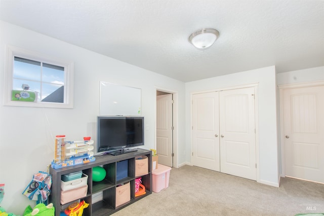 playroom featuring a textured ceiling, baseboards, and light colored carpet