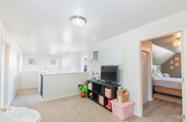 rec room featuring lofted ceiling, baseboards, a textured ceiling, and light colored carpet