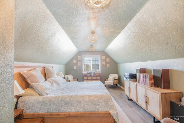 bedroom featuring lofted ceiling, a textured ceiling, and wood finished floors