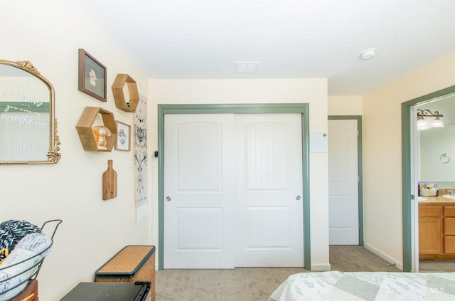 bedroom featuring connected bathroom, a closet, light carpet, and a sink