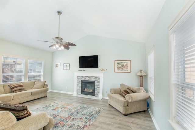 living room with baseboards, lofted ceiling, ceiling fan, a fireplace with flush hearth, and light wood-type flooring