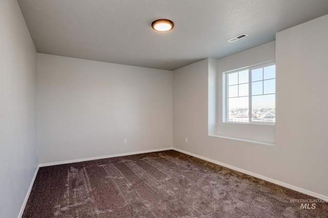 spare room featuring visible vents, baseboards, a textured ceiling, and carpet flooring