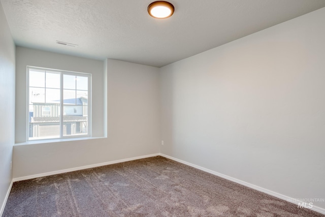 carpeted spare room featuring visible vents, a textured ceiling, and baseboards