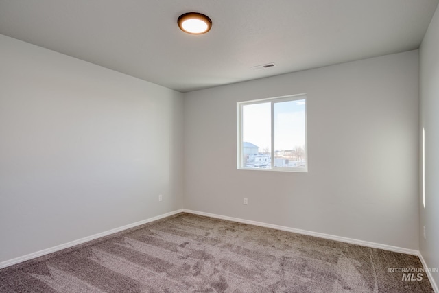 carpeted spare room with visible vents and baseboards