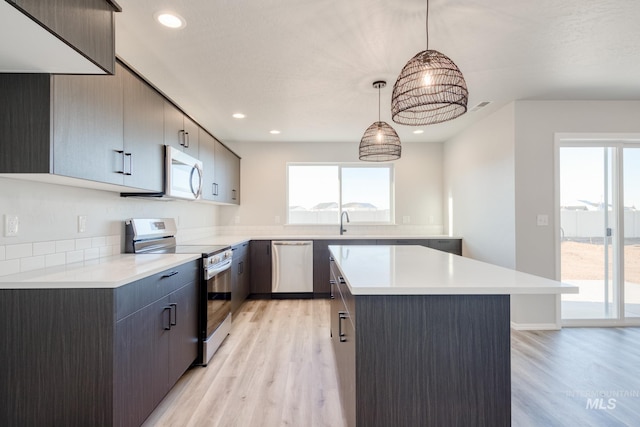 kitchen with a center island, light wood-type flooring, stainless steel appliances, and light countertops