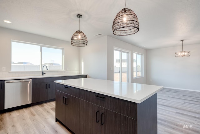 kitchen with visible vents, a kitchen island, light wood-style floors, light countertops, and dishwasher