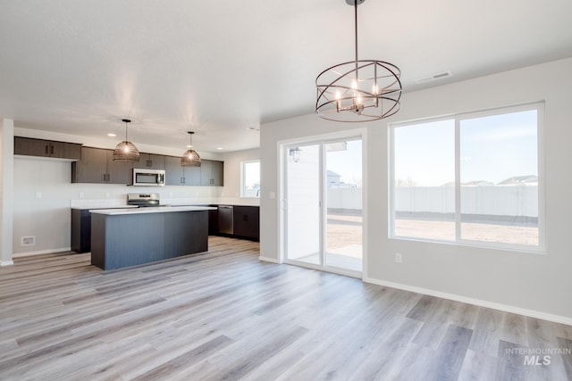 kitchen with visible vents, a kitchen island, light countertops, an inviting chandelier, and stainless steel appliances