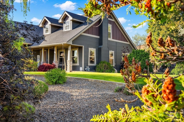 view of front of property featuring board and batten siding, covered porch, a front lawn, and roof with shingles