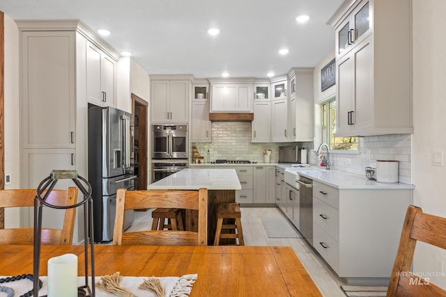 kitchen featuring stainless steel appliances, a sink, light countertops, tasteful backsplash, and recessed lighting