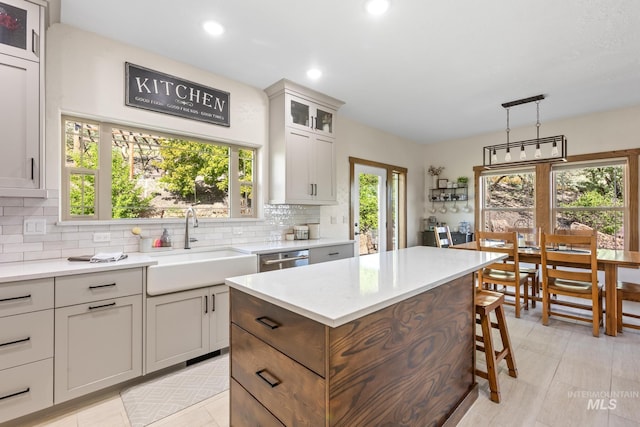 kitchen featuring a sink, backsplash, recessed lighting, a kitchen island, and glass insert cabinets