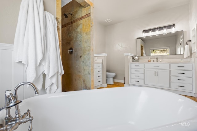 bathroom featuring vanity, a soaking tub, tiled shower, and toilet