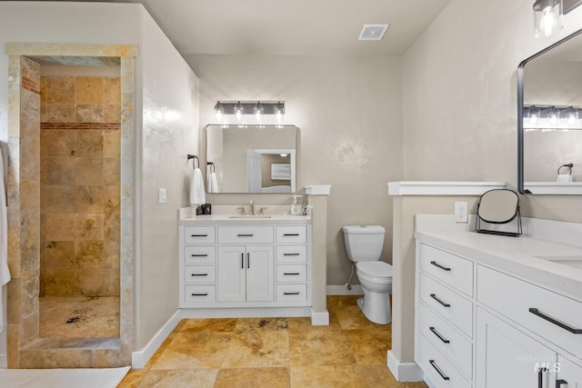 full bath with a tile shower, baseboards, toilet, and two vanities