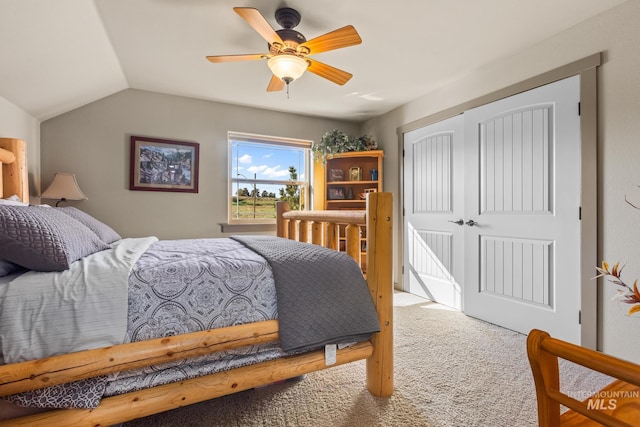 carpeted bedroom with a closet, lofted ceiling, and a ceiling fan
