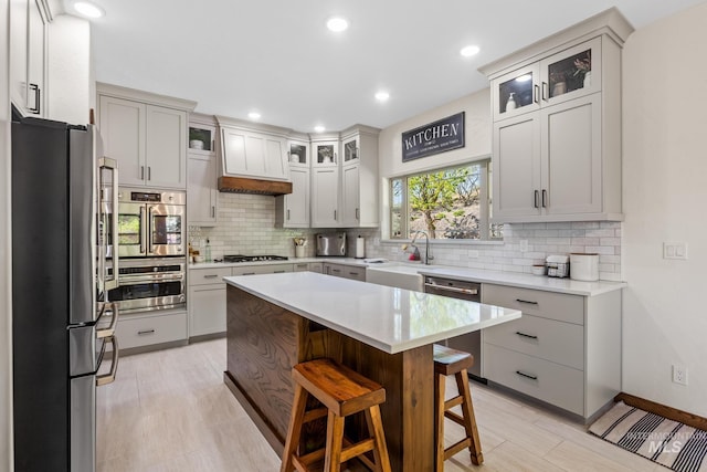 kitchen with appliances with stainless steel finishes, a kitchen breakfast bar, decorative backsplash, light countertops, and recessed lighting