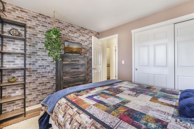 bedroom featuring a closet, brick wall, and wood-type flooring